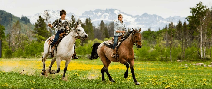 Confident plus-size woman riding Scottish a horse through a field with a smile on her face.